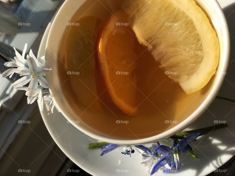 Tea with lemon decorated with fresh flowers in minimalist white porcelaine mug 