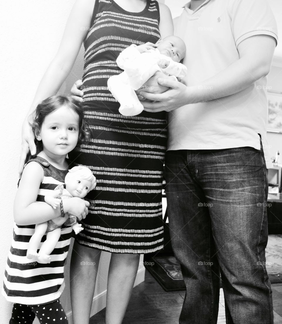 Little girl holding doll standing with mother and father