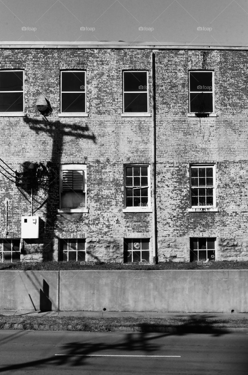 Electric pole shadow against brick factory building