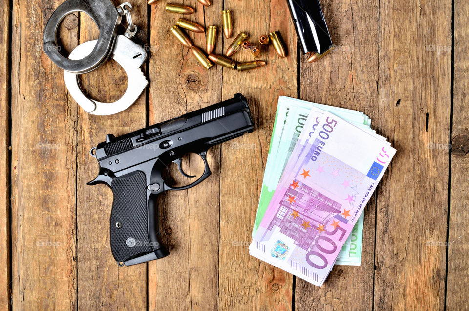 Background with 9mm pistol gun, euro banknotes, handcuffs and bullets