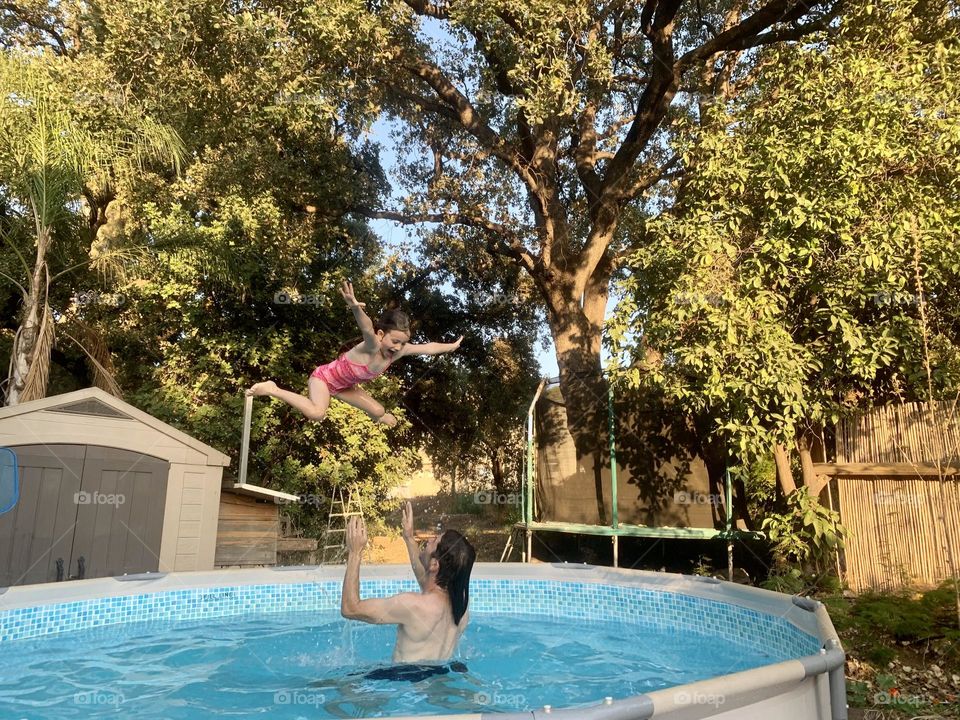 Dad and his daughter having fun in backyard pool