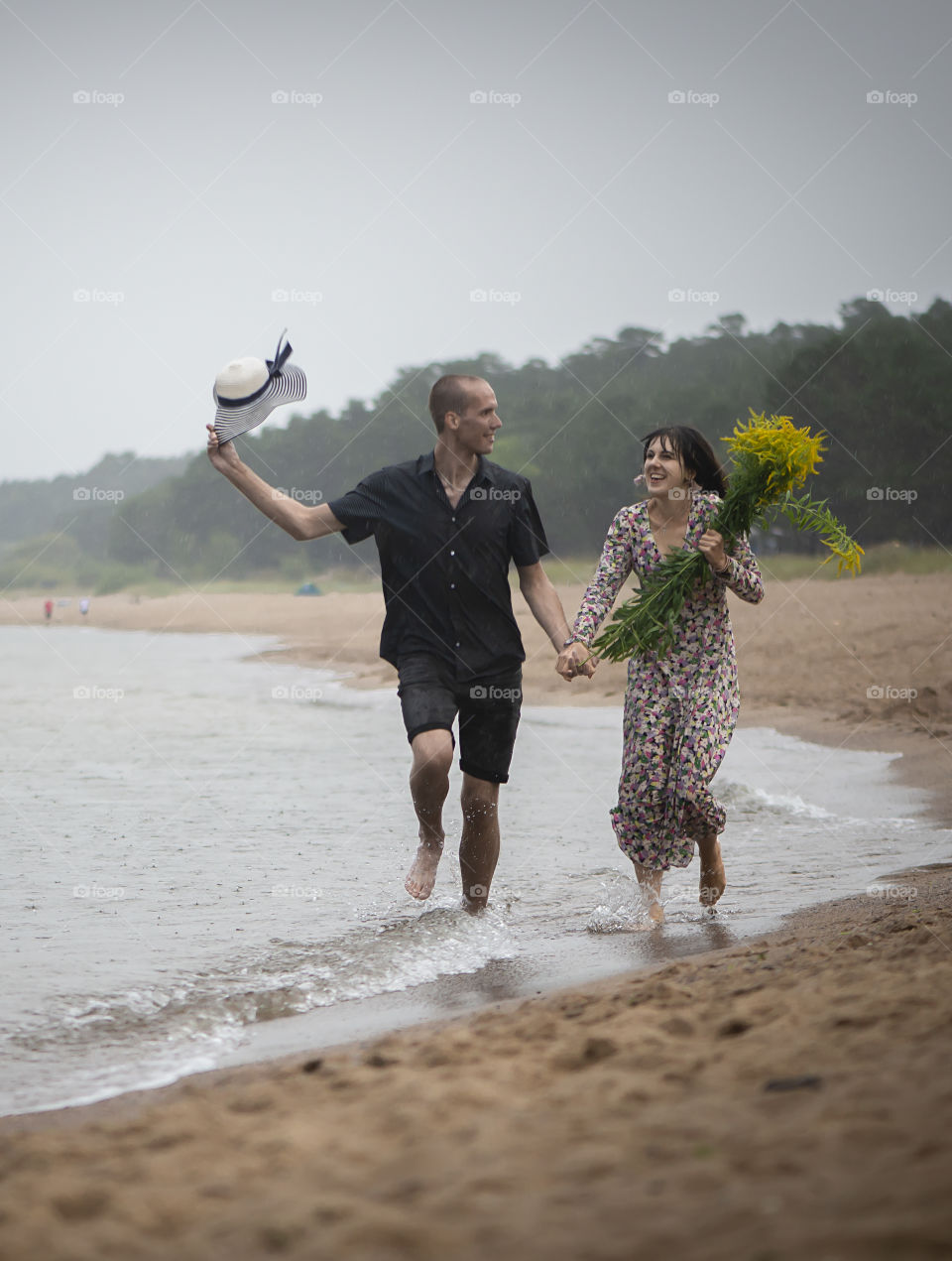 Happy couple having fun in rainy day at the beach