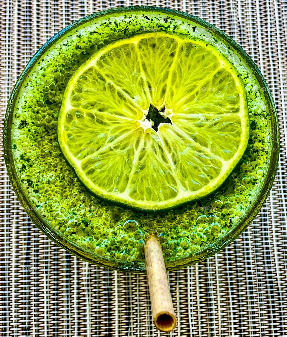 A green juice drink topped with a slice of lime.