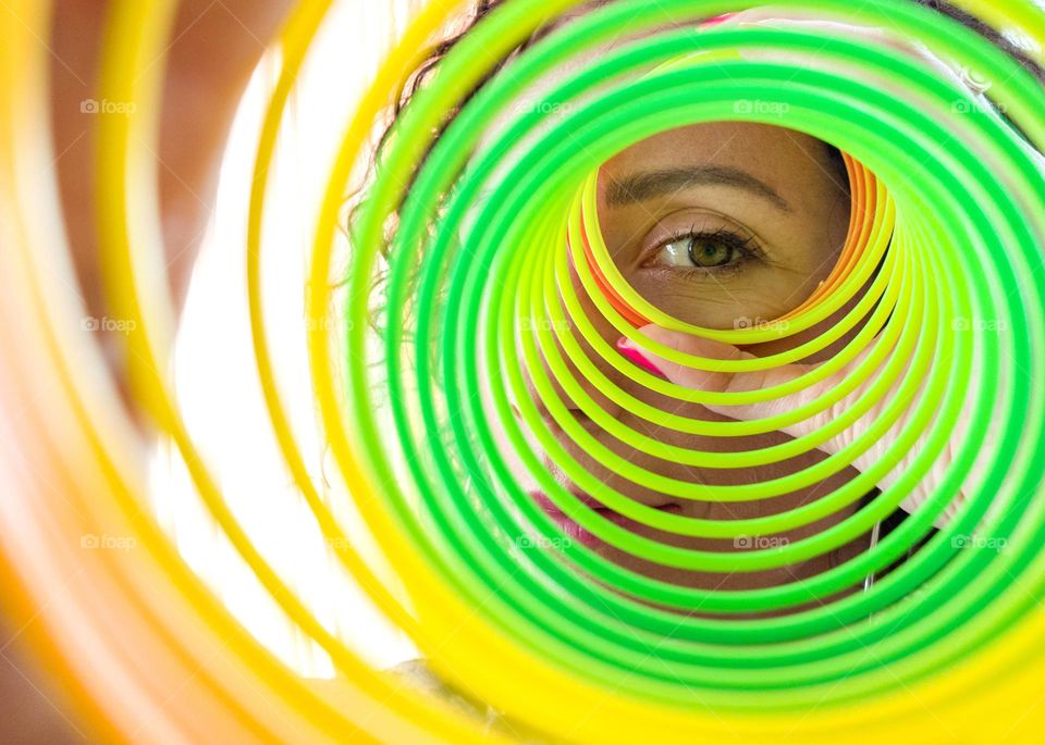 Circle, A Woman Looks through Rainbow Spring Toy