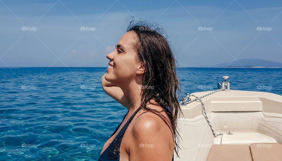 Side view portrait of happy young woman on boat during summer vacation