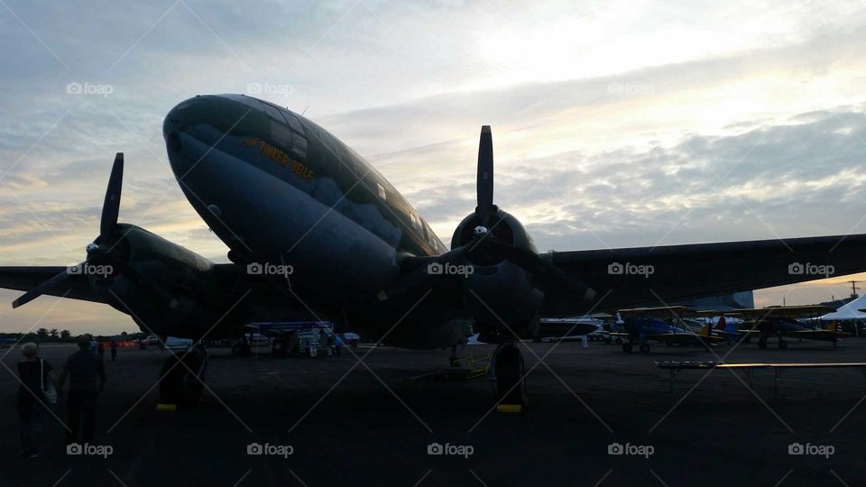 WWII airplane in sunset sky at runway