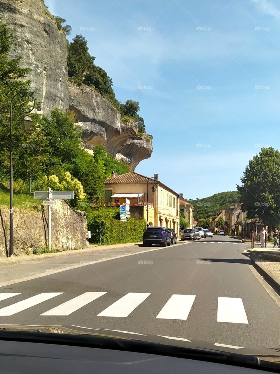 A road-trip allows you to discover amazing landscapes and magnificent cities. In the foreground of this photo, a pedestrian crossing. In the background, a house overlooked by the rock.