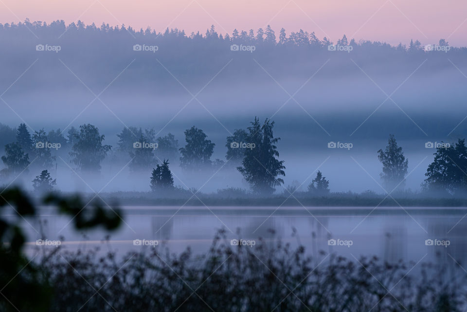 Foggy summer landscape by the lake in Finland after sunset