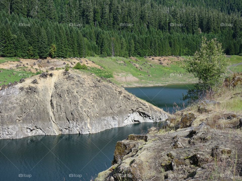Rock outcropping on the steep shoreline of Cougar Reservoir in the forests of Western Oregon on a sunny summer day. 