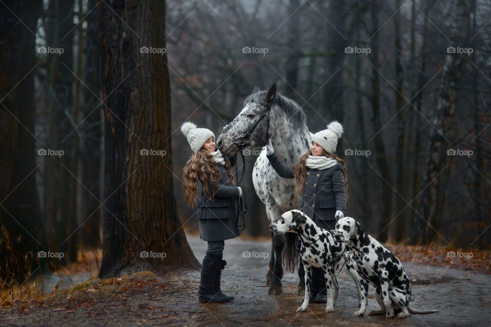 Twins girls with Appaloosa horse and Dalmatian dogs in autumn park 