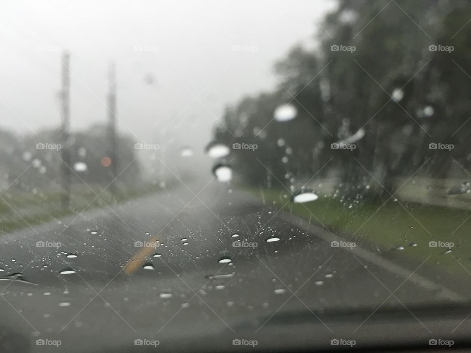 Raindrops on the Windshield . Close up of rain drops on a rainy day with wet roads.  