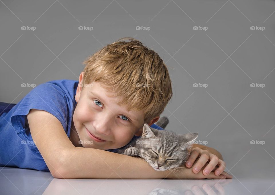 The little boy and his kitten are happy together.