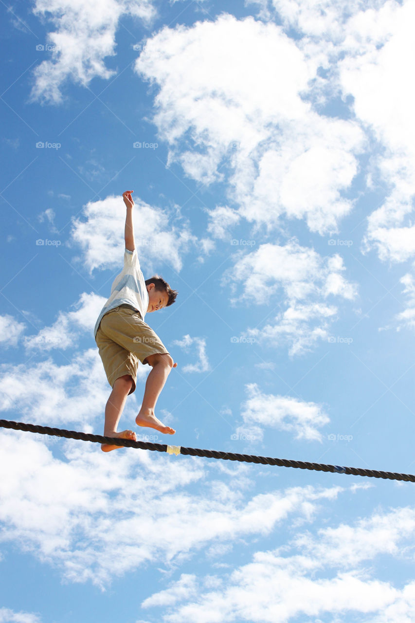 Low angle view of boy balancing on tightrope