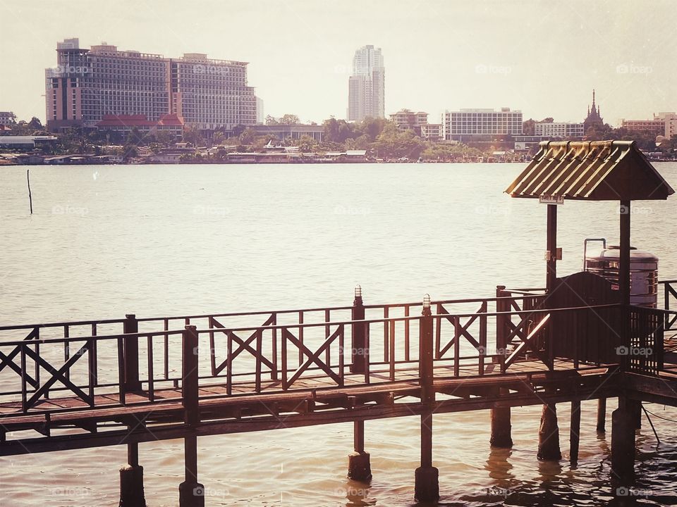 Walk bridge near a harbor and tall buildings in the background.