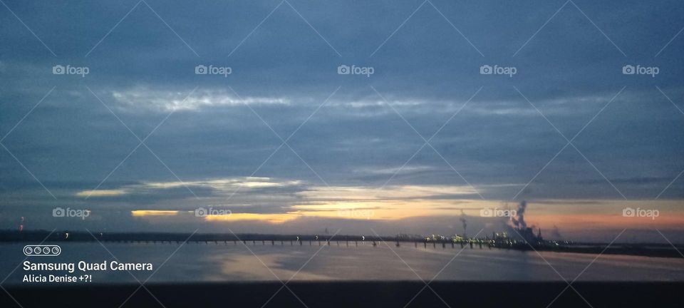 A bridge with a sky at sunset taken from a highway 