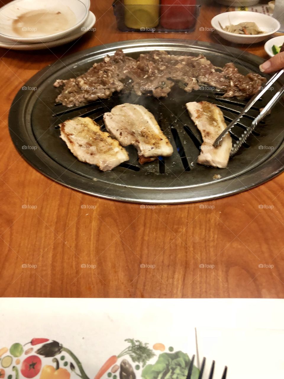 Pork and beef on table grill at Korean BBQ restaurant.
