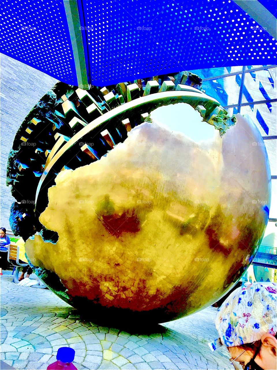 This large golden sphere, a sculpture is on permanent display at Mt Sinai hospital on Manhattan’s Upper East Side. It looks like a cracked Christmas ornament revealing insides like the inner workings of a precision watch. 2021. Hypnotic Productions 