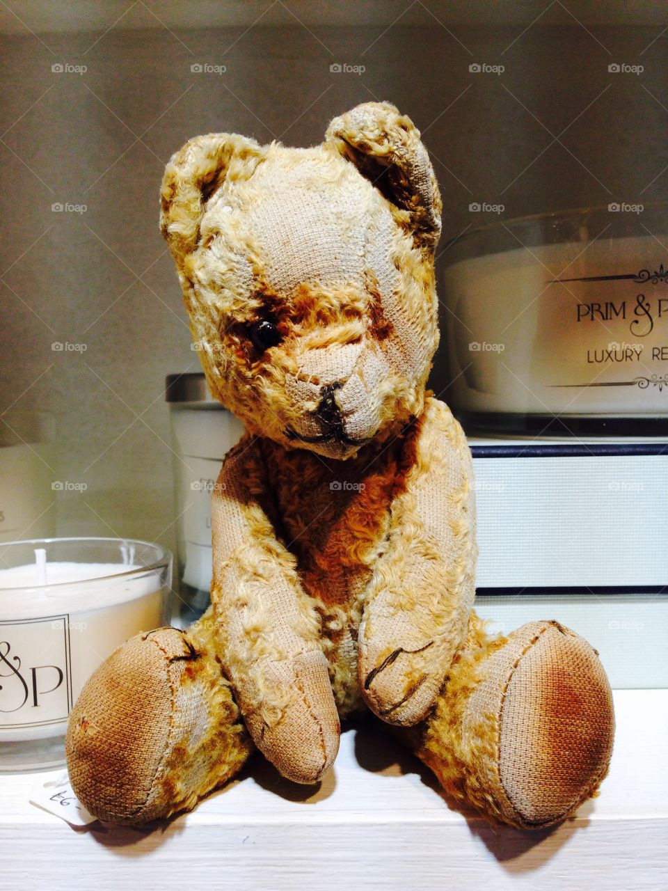 Old ted on the candle shelf. A much loved old vintage teddy bear sat on a candle shelf 