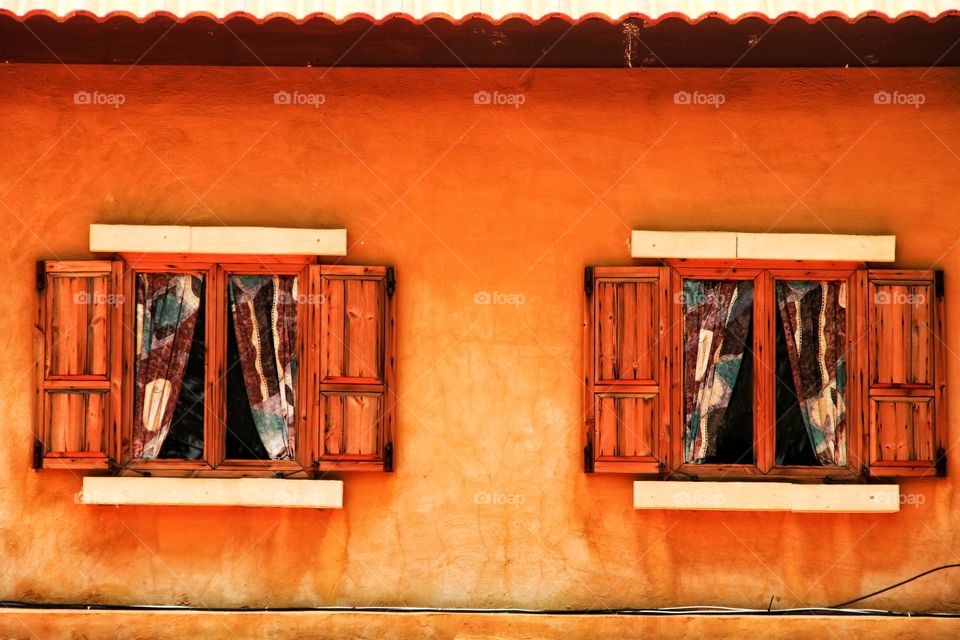 Beautiful two wooden windows on orange wall.