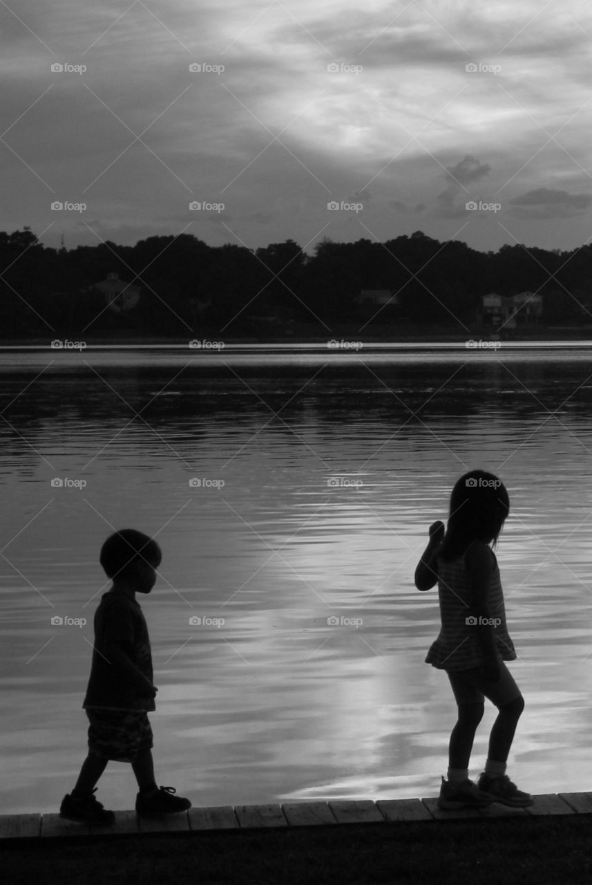 A brother and sister walk the plank at the park in front of a magnificent sunset!