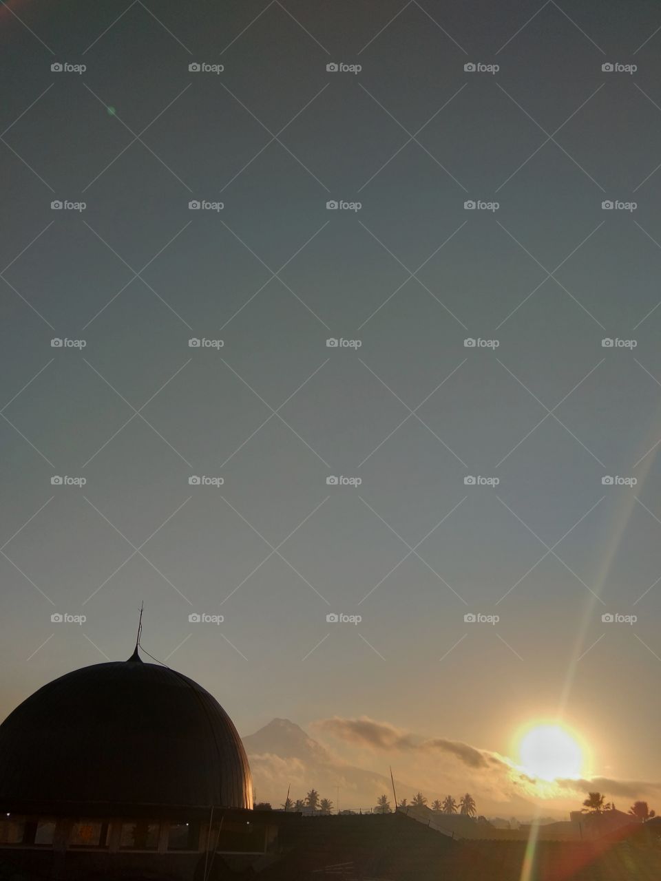 the view of the sun rising with the dome looks like a silhouette