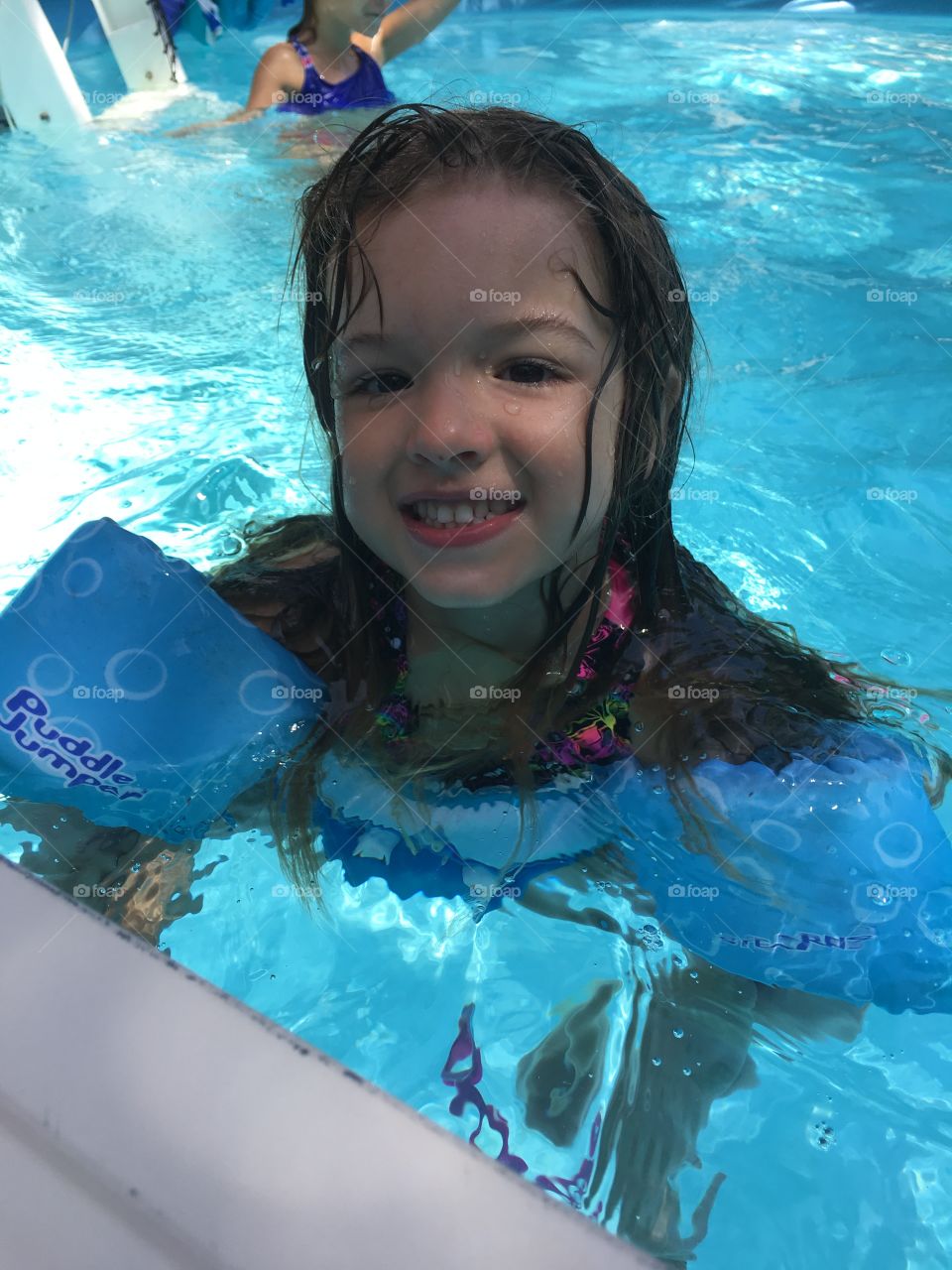 Portrait of a girl in swimming pool with armband