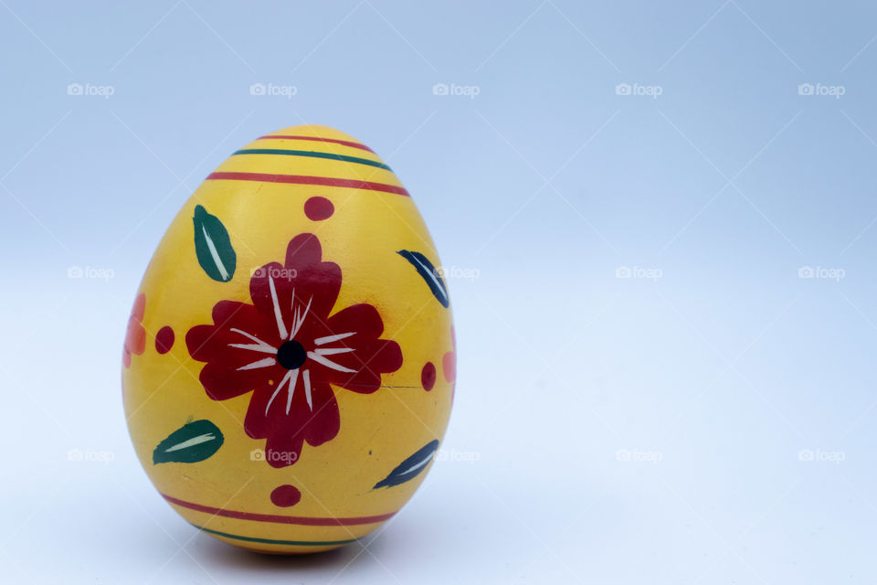 Single wooden yellow Easter egg with patterns on white background