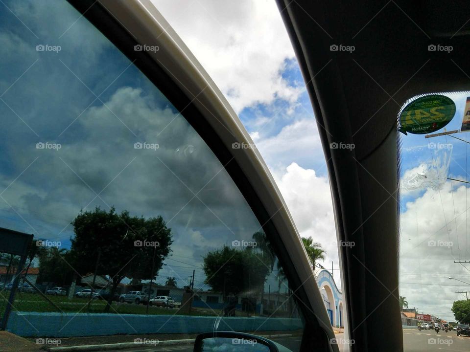 O lindo céu azul e as nuvens brancas, da janela com insulfilm do meu carro.