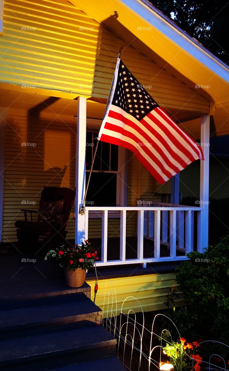Patriotic American flag on vintage yellow cottage 