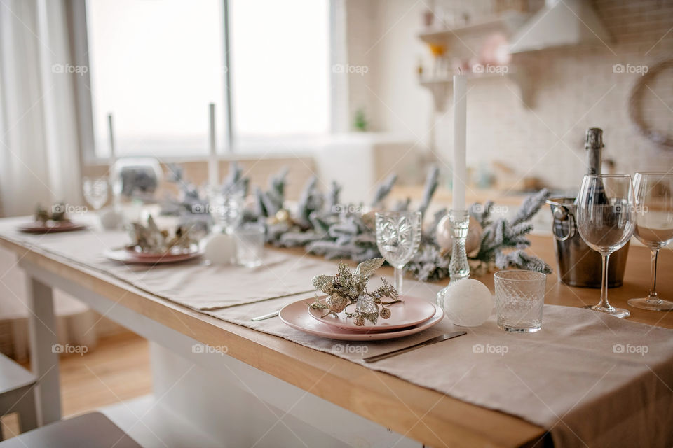 Festive winter cozy kitchen interior with garlands, decorations and gifts.  Christmas dinner at the decorated table.