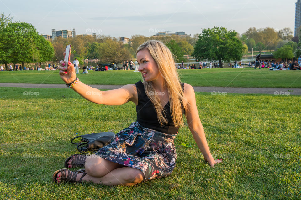 Woman tourist from Sweden 30 years plus taking a selfie in Hyde park in London.