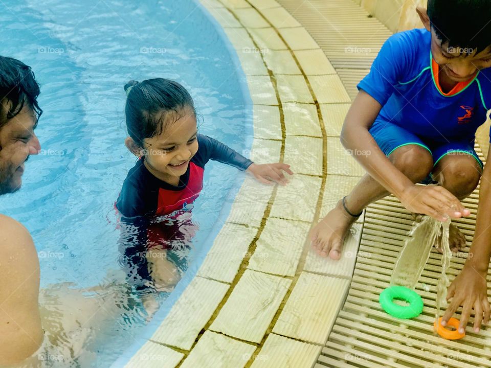 A father son and daughter enjoying a lot at swimming pool in summertime 