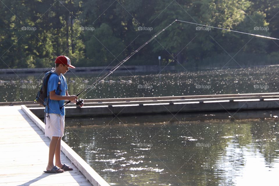 Boy fishing for bass off dock in Summer