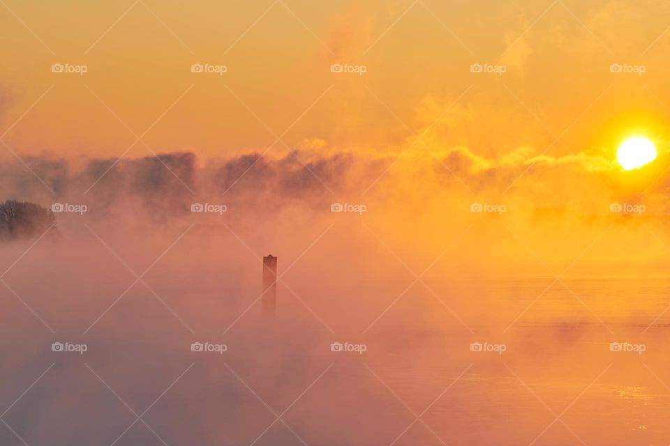 Almost completely frozen Baltic sea in extremely cold weather in Helsinki, Finland with thick sea smoke rising from the Baltic sea at sunrise in January.