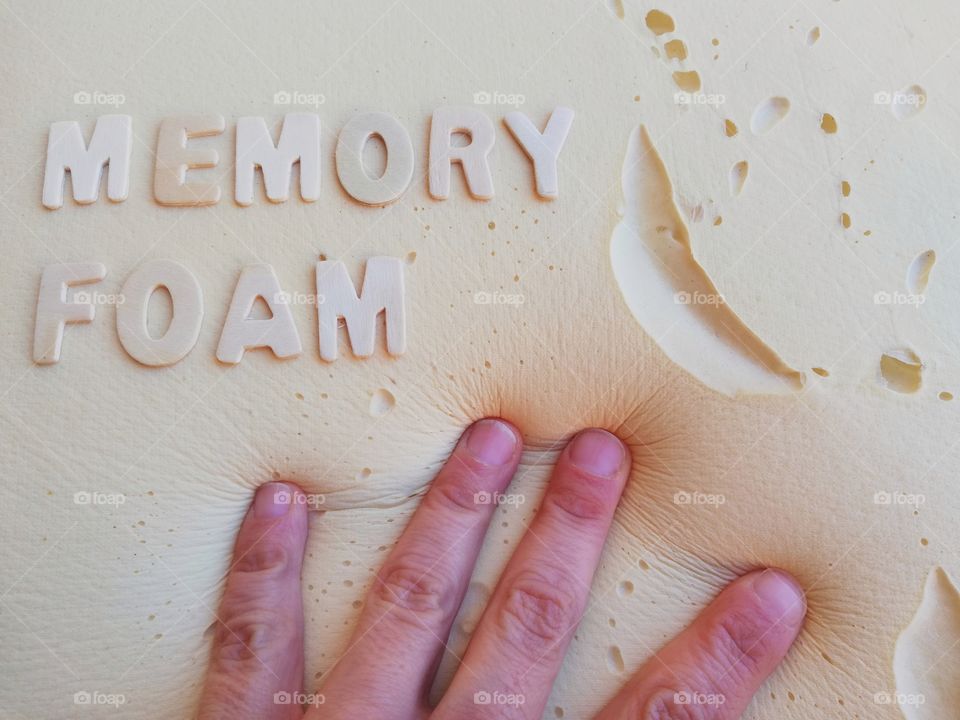 Inscription: "memory foam" on a memory foam background and an hand