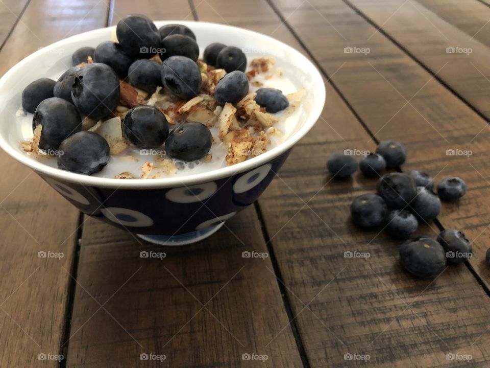 Blueberries on a bowl of coconut granola with almond milk 