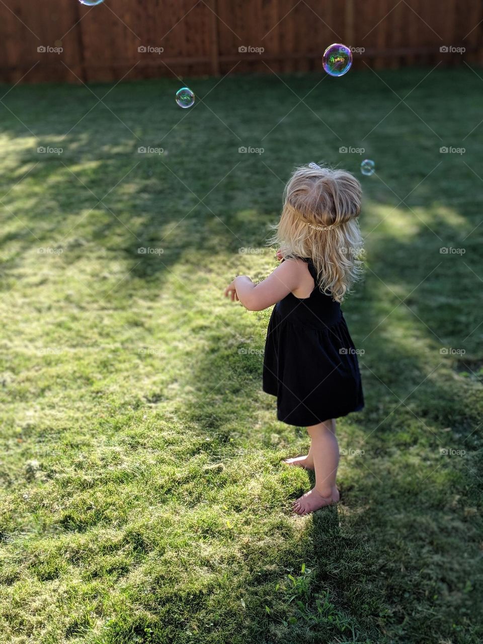 girl in the green grass on a summer night with bubbles in the air