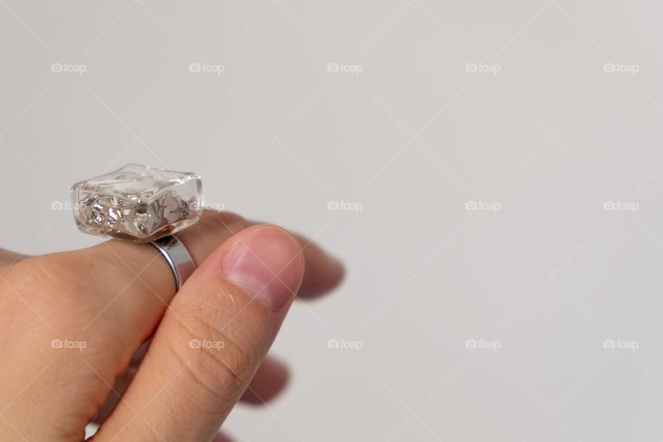 Ring with shimmer on a finger on a beige background