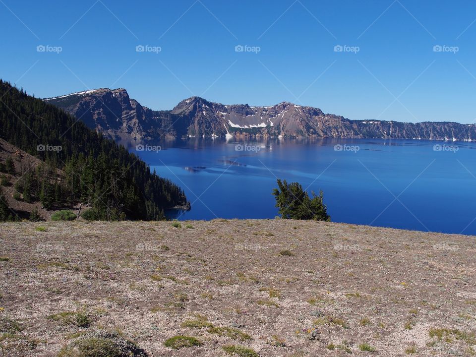 The rugged rim reflecting in the stunning Crater Lake on a beautiful summer morning in Southern Oregon. 