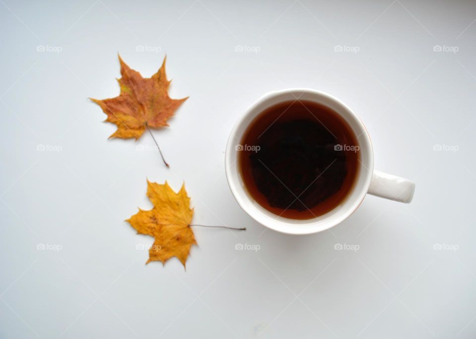 cup of tea with two autumn leaves top view
