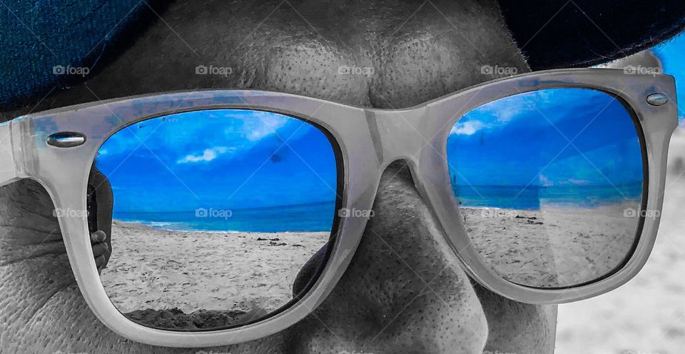 Ocean and blue skies reflected in sunglasses 