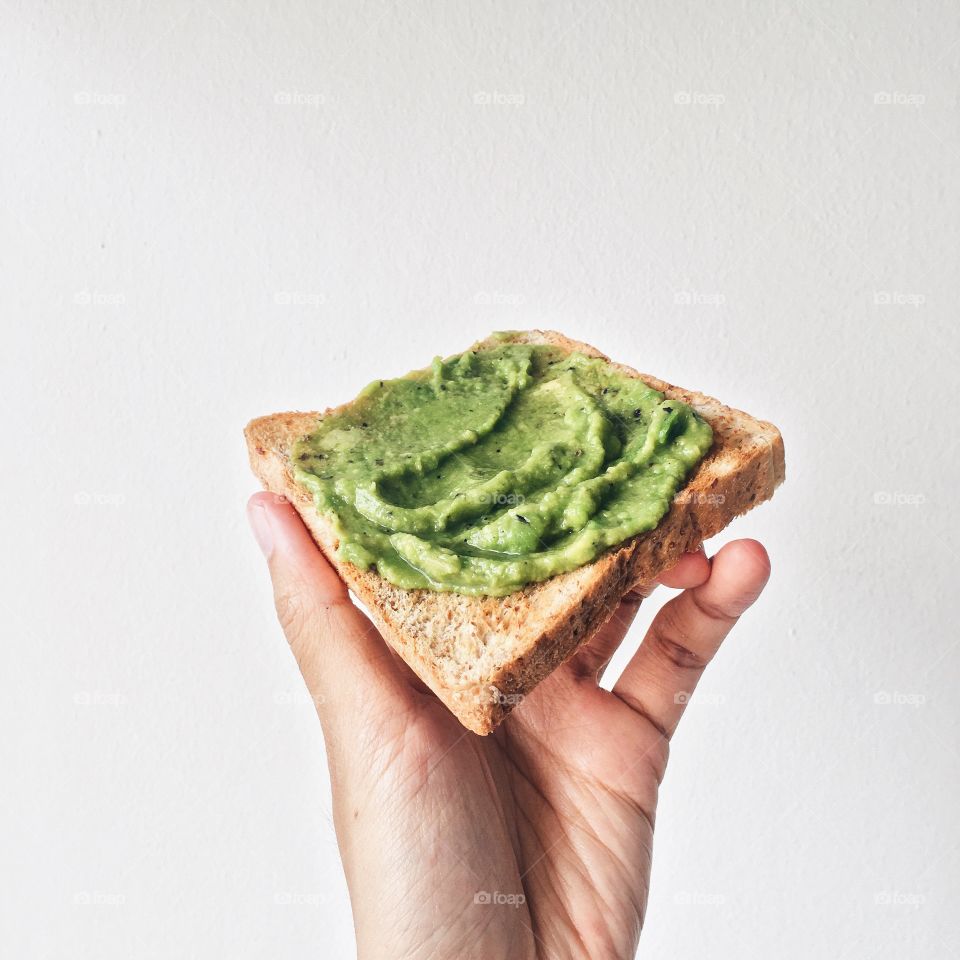 Studio shot of hand holding avocado toast