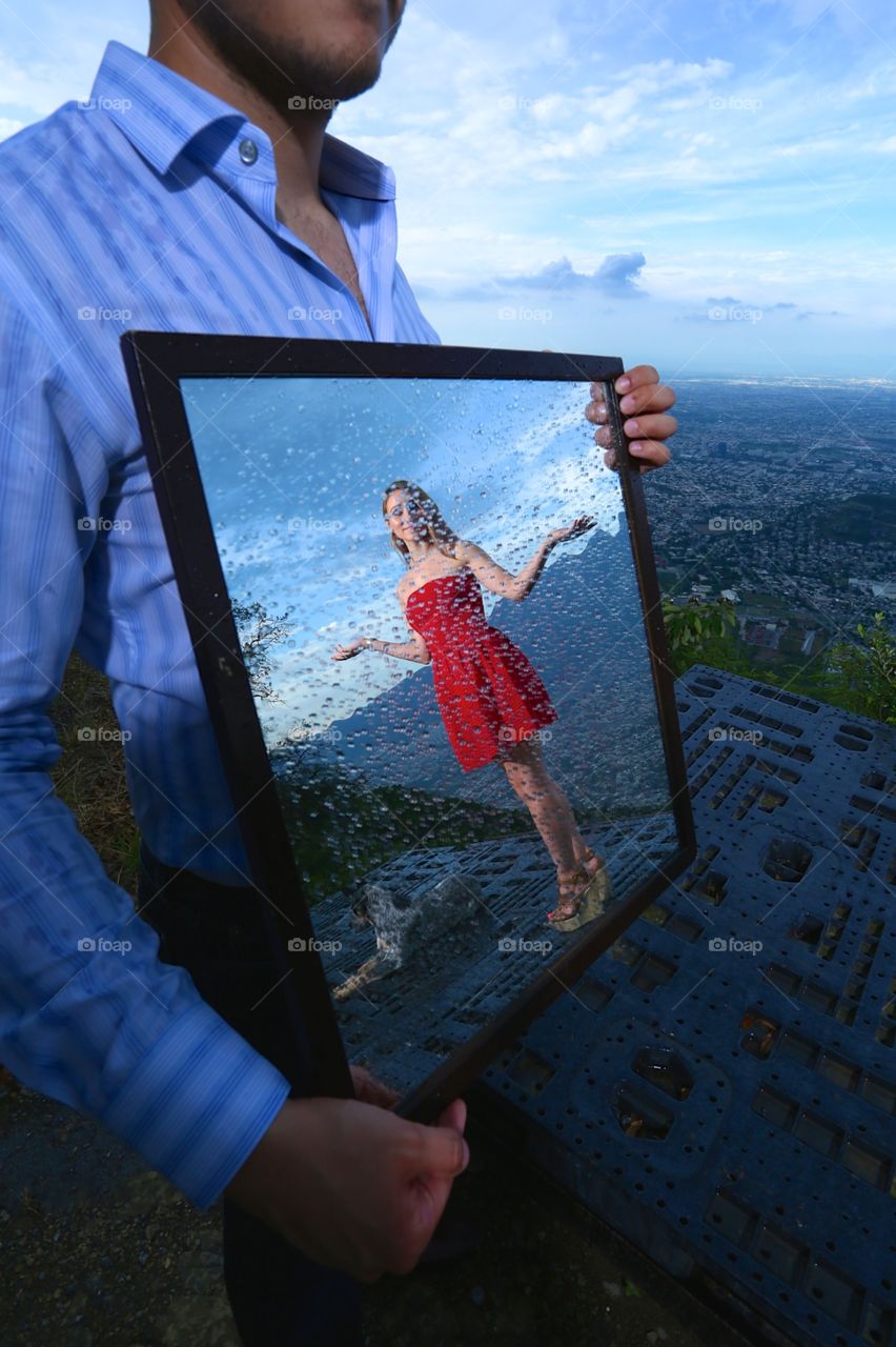 Raindrops on the mirror. There's a woman in red dress appearing on a misty wet mirror, feeling the rain
