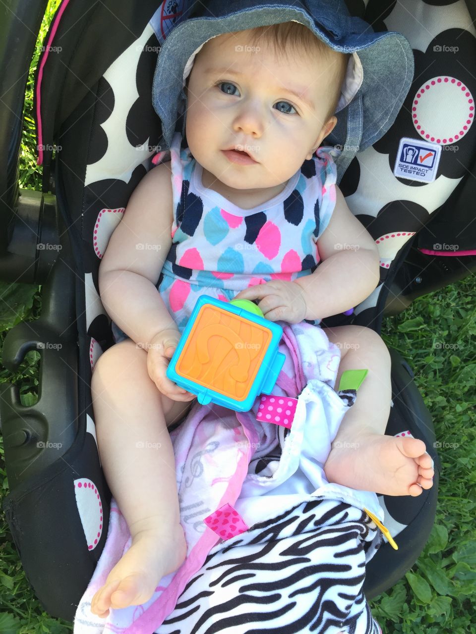 Portrait of baby girl sitting in stroller with toy