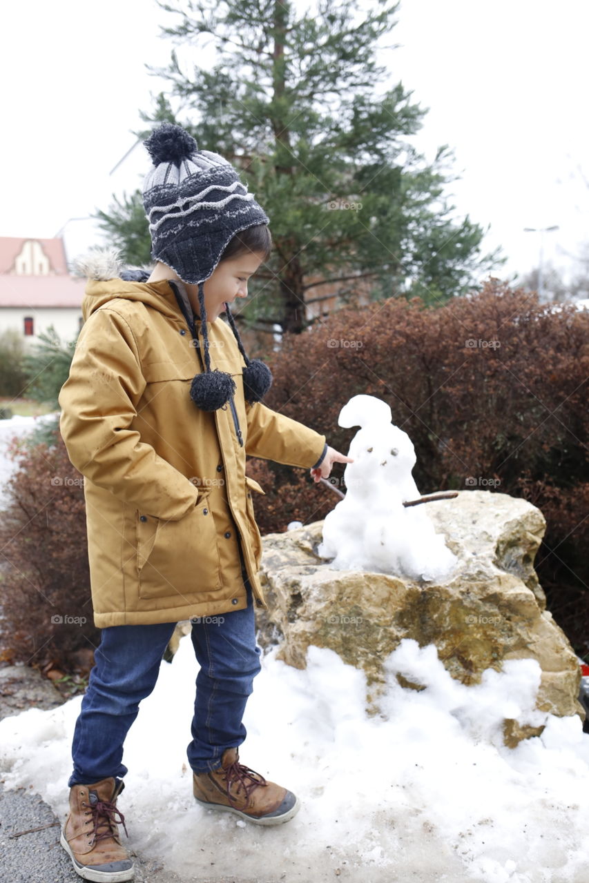 boy is playing with a snowman