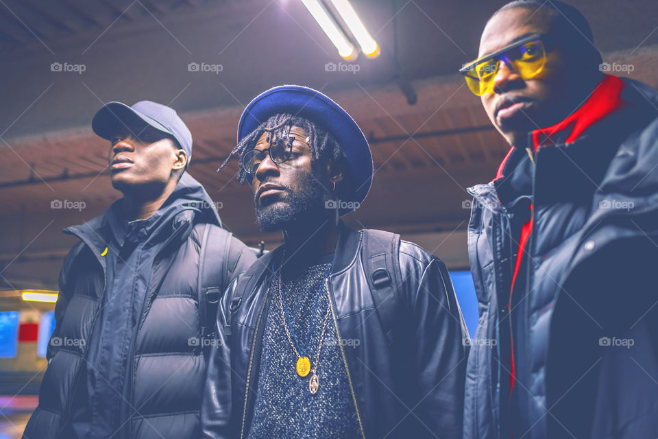 Three black young men posing in the city by night looking at the future - black power concept, street fashion