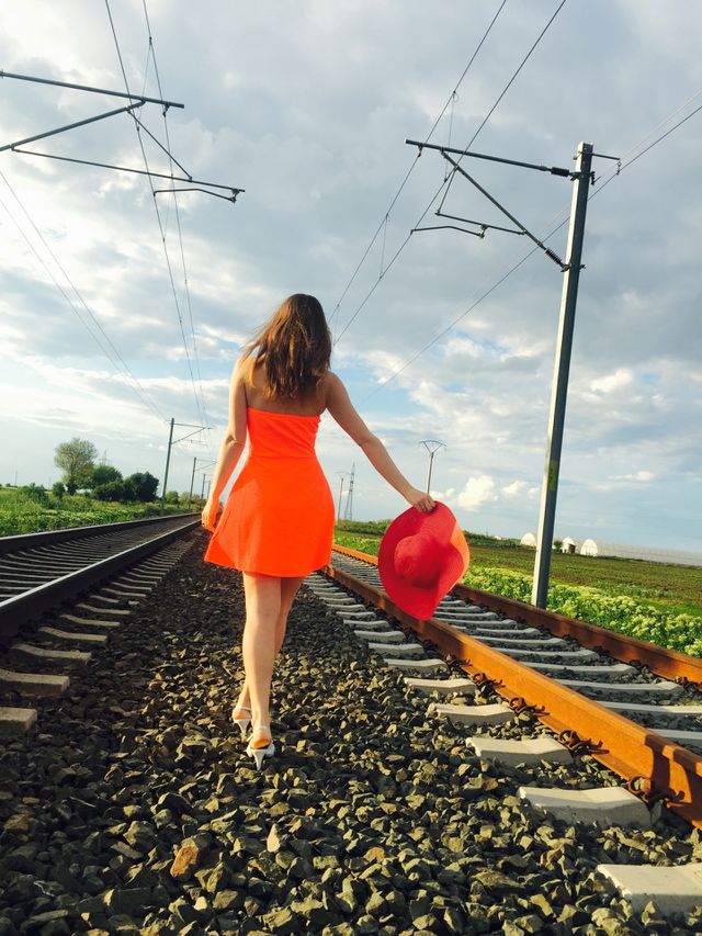 Rear view of woman walking on railroad holding hat