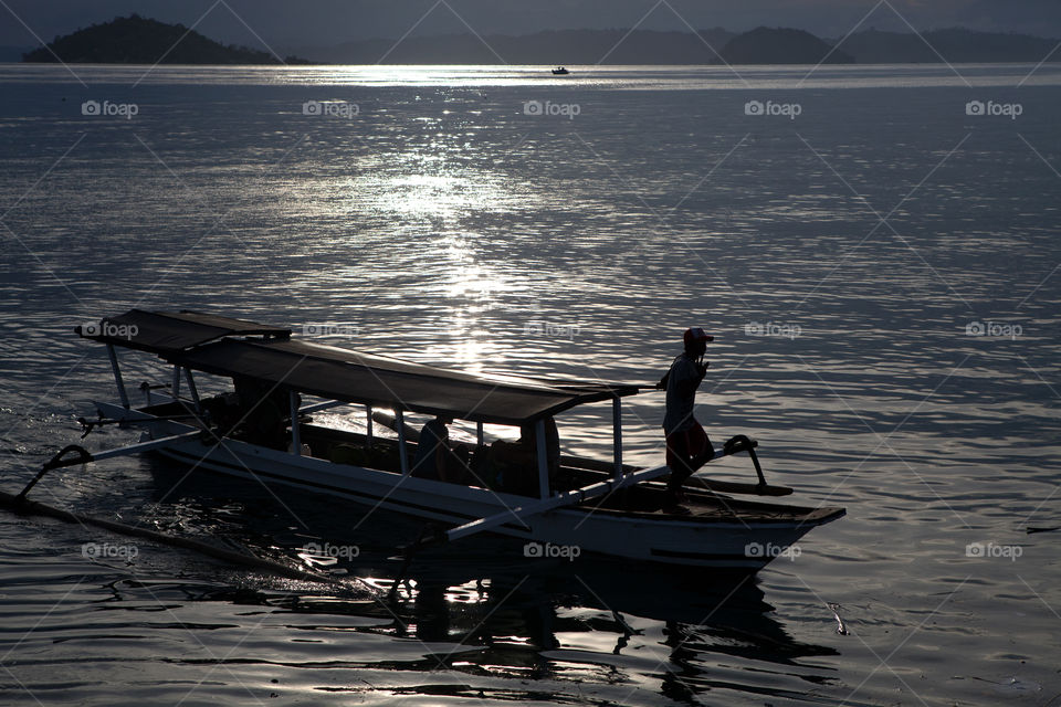 Silhouette of a man piloting a boat at dusk. Sulawesi, Indonesia 