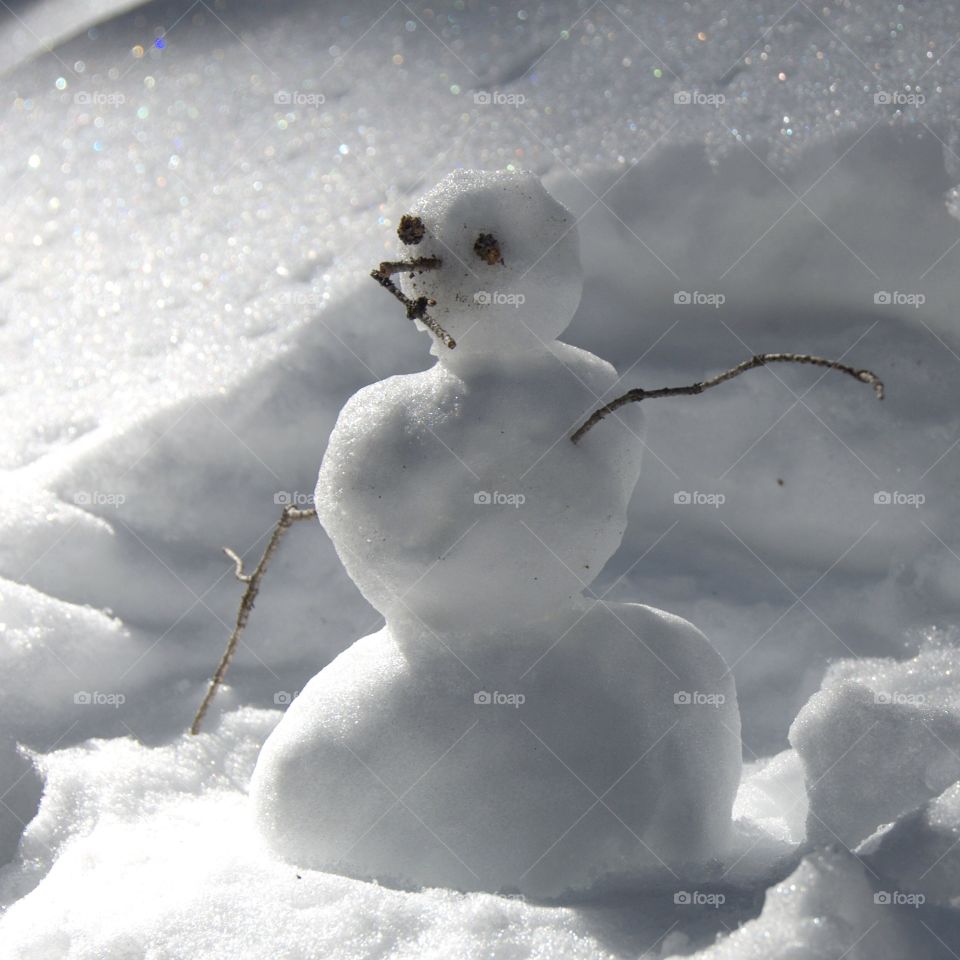 A tiny snowman creates a silly scene on a cold winter day. This shot is cute and sparkly.