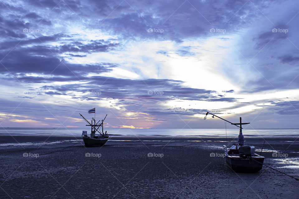 The morning sun light in the sea and the boat on the beach.